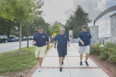 Coaches Mike Sewak, Paul Johnson, and Ron West pass the Ken Byers Tennis Complex during a recent walk. Photo by Christopher Moore